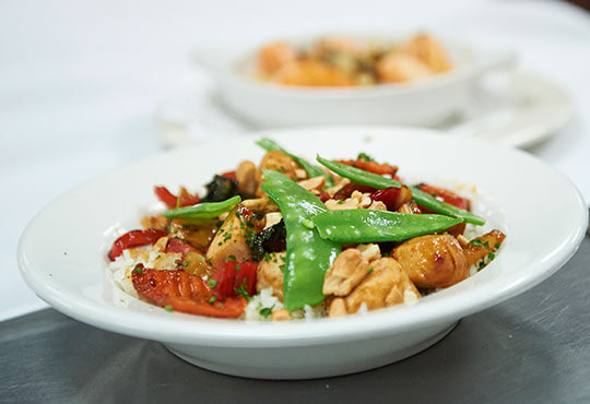 White bowl of rice, chicken, peppers and vegetables.