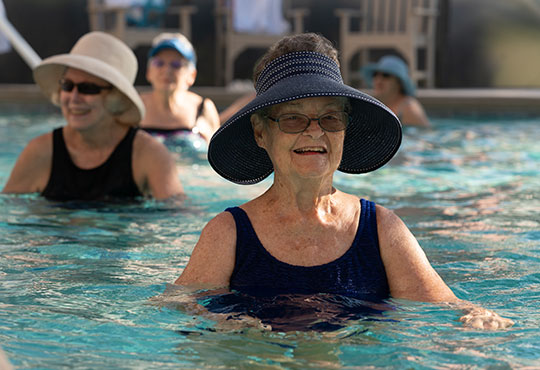 Group of senior women using water weights for a water aerobics fitness class.