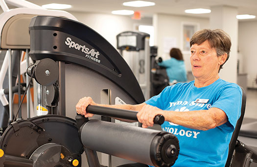 Older woman using a fitness machine in a gym.