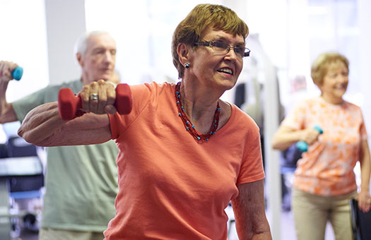 Senior woman using weights in a group fitness class.