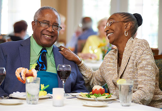 Couple laughing while eating dinner in the John Knox Village dining room.