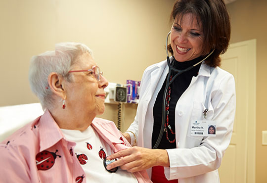 Female nurse practitioner listening to the heart of a female senior patient.