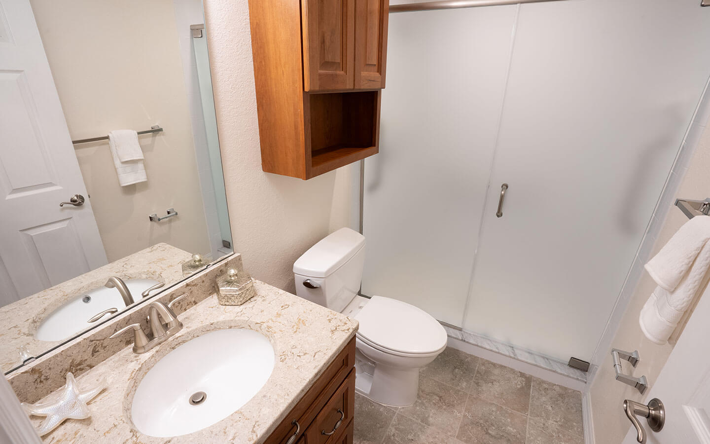 Bathroom with single sink, toilet and walk-in shower.