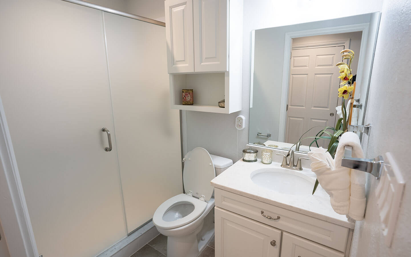 Bathroom with single sink, toilet and walk-in shower.