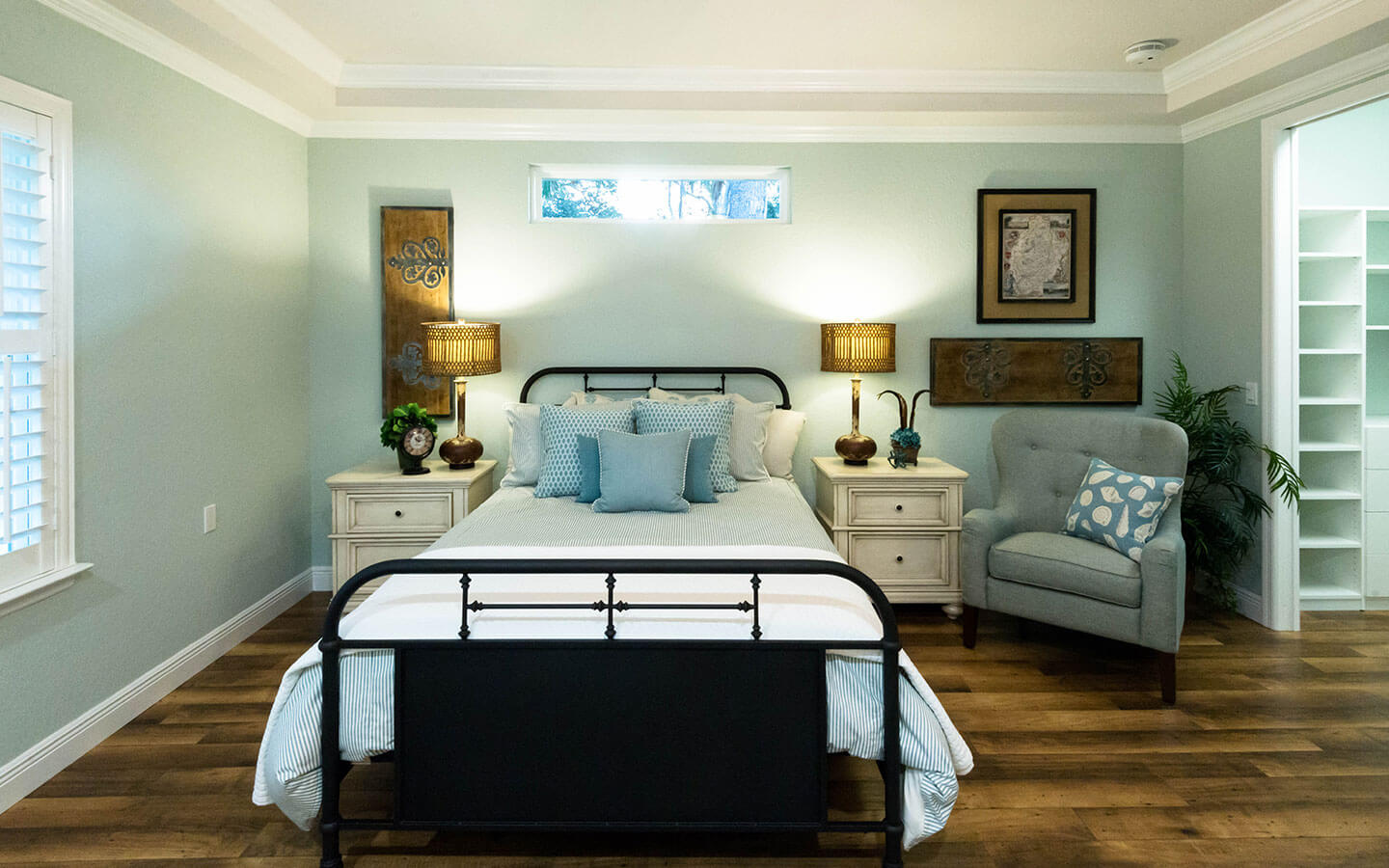 Bedroom with large bed and winged back chair with site tables and lamps.