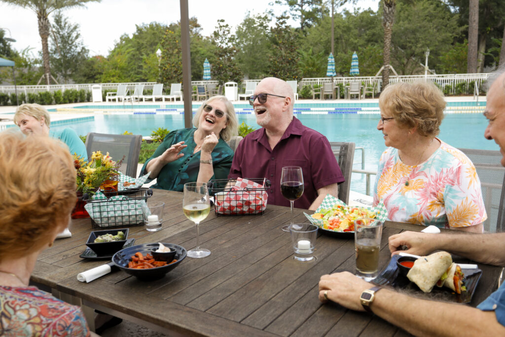 Senior friends sitting around a table outdoors.